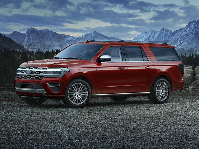 An image of a metallic dark red Ford Expedition Max against a backdrop of mountains. 