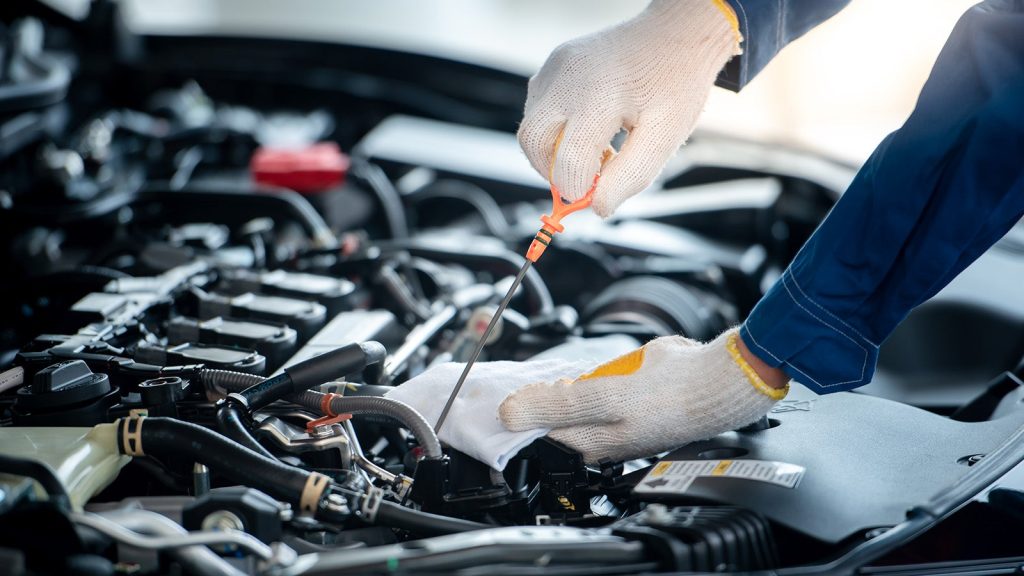 A closeup of a service technician checking the fluids in a car during routine maintenance