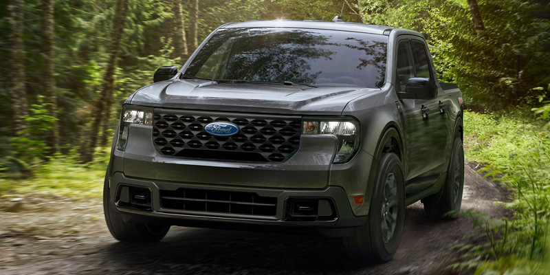 a black 2026 Ford Maverick truck drives down wooded back road near O'Fallon, IL