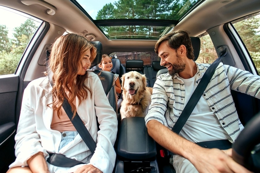 Happy family and dog enjoying a summer road trip in a Ford